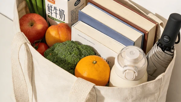 A realistic lifestyle product photo of a sturdy woven cotton canvas tote bag filled with groceries, books, and everyday essentials, showing structure and load-bearing capacity, natural daylight, minimal modern setting, premium reusable bag photography, detailed fabric texture, no text, no watermark A realistic lifestyle product photo of a sturdy woven cotton canvas tote bag filled with groceries, books, and everyday essentials, showing structure and load-bearing capacity, natural daylight, minimal modern setting, premium reusable bag photography, detailed fabric texture, no text, no watermark